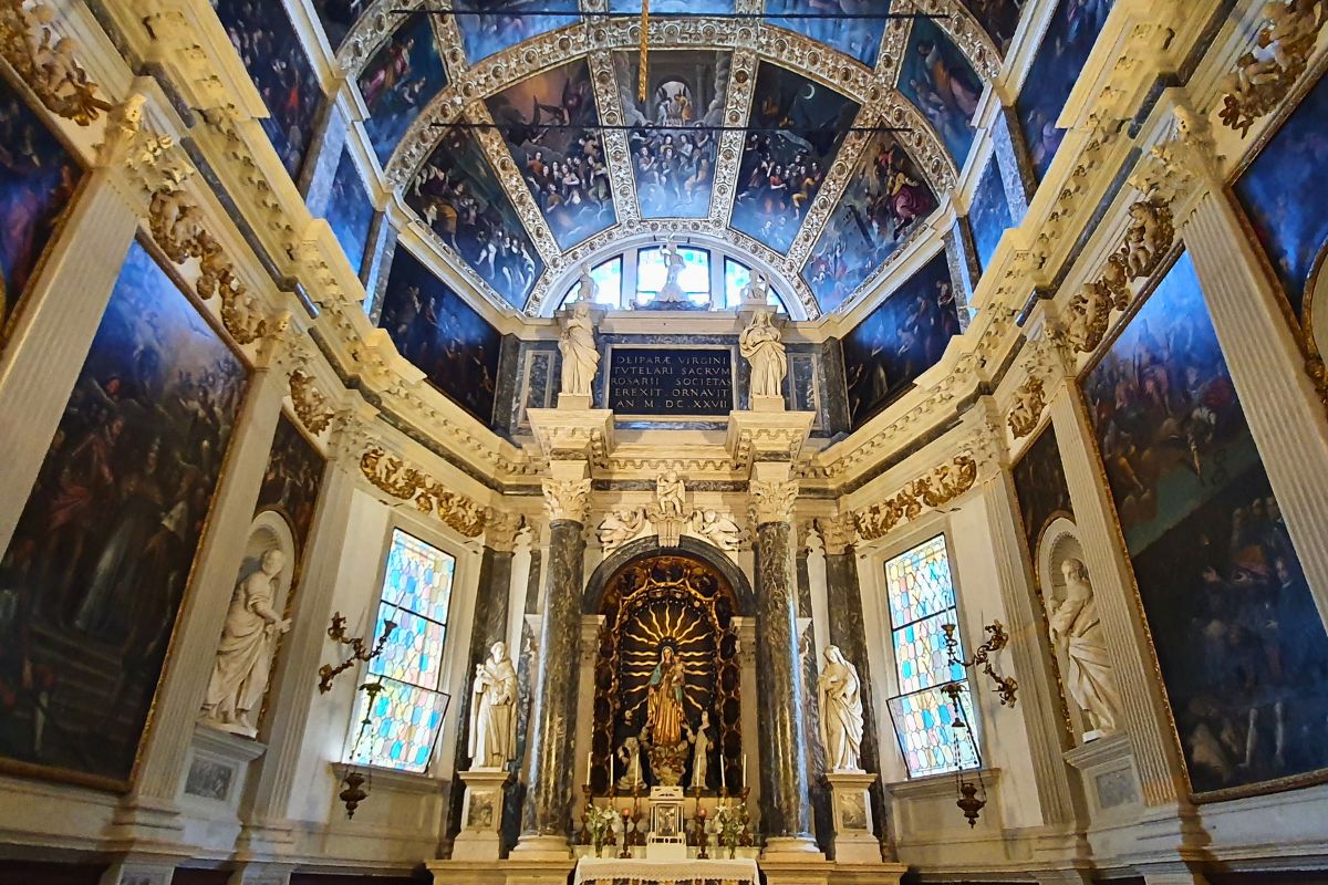 Blick in die beeindruckende Cappella della Vergine del Rosario in der Kirche Santa Corona. Der Raum ist reich geschmückt mit großen Ölgemälden an den Seitenwänden und einem Altar unter einer bemalten Gewölbedecke.