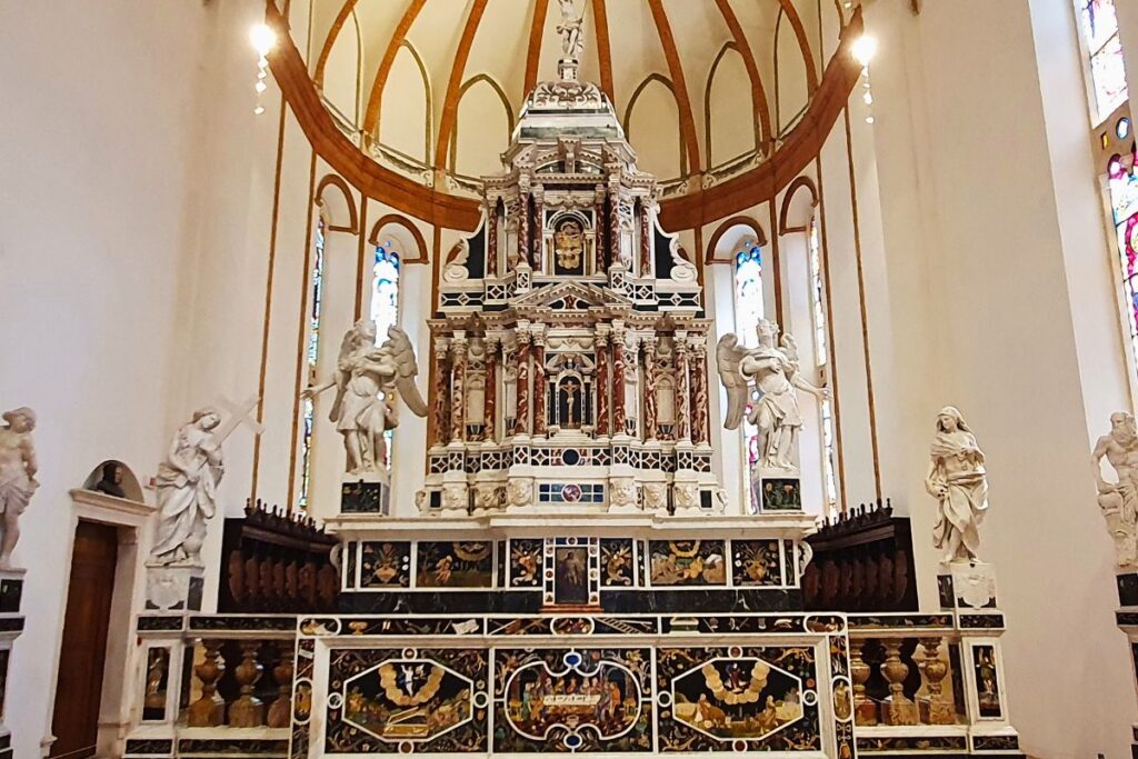 Der prächtige Hochaltar von Santa Corona mit aufwendigen Marmor-Intarsien (bunten Steineinlegearbeiten), flankiert von weißen Statuen und Buntglasfenstern.