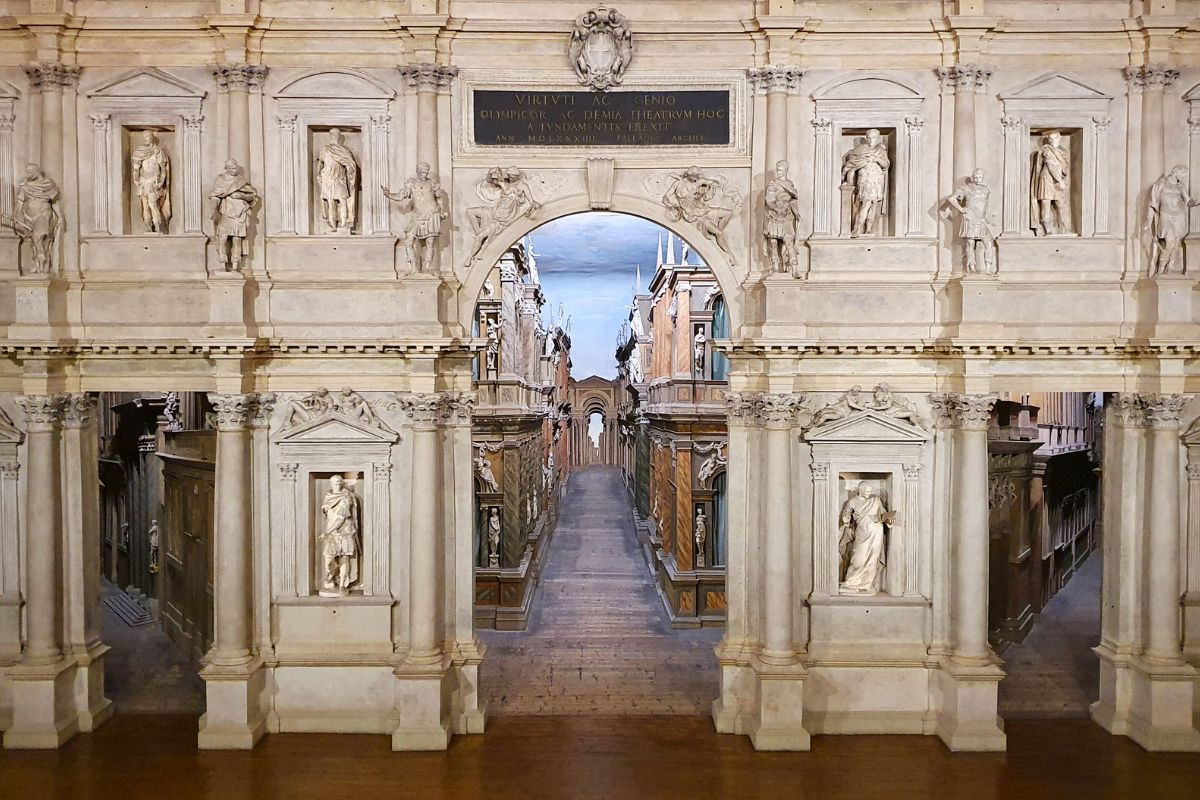 Blick auf die berühmte Bühne des Teatro Olimpico in Vicenza mit der hölzernen Stadtkulisse ("Die sieben Straßen von Theben"), die durch erzwungene Perspektive unendlich lang wirkt.