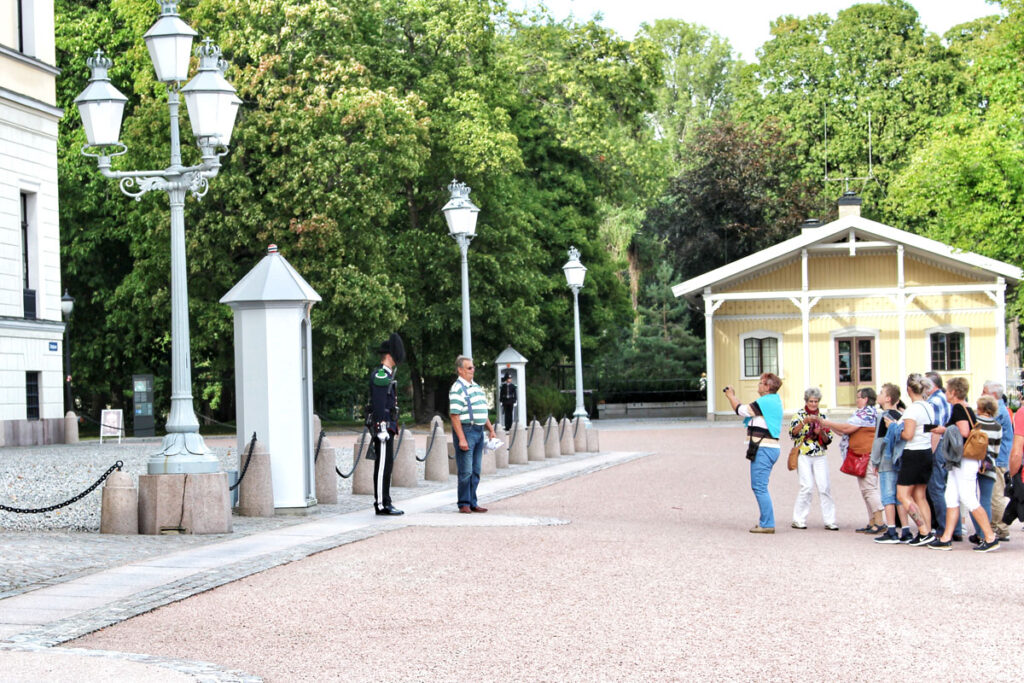 Soldat der Königlichen Garde vor seinem Wachhäuschen am Schloss Oslo, beobachtet von einer Gruppe Touristen