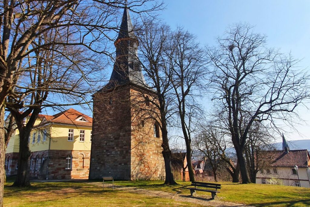 Der historische Karlsturm auf dem Schulberg in Eschwege, umgeben von blattlosen Bäumen und einer Parkanlage im Sonnenlicht.