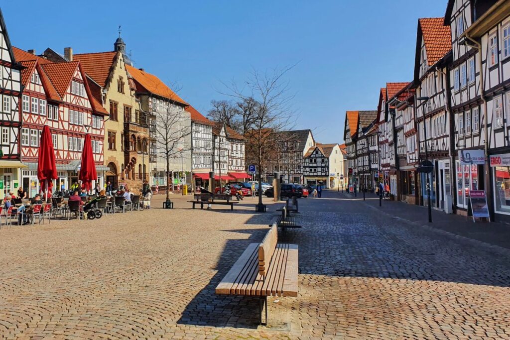 Der weitläufige Marktplatz in Eschwege mit historischen Fachwerkhäusern, Sitzbänken und dem Rathaus unter strahlend blauem Himmel.