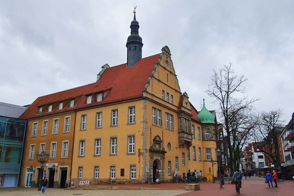 Das ehemalige Rathaus von Gütersloh, ein großes gelbes Gebäude mit rotem Dach und Turm, das heute von der Polizei genutzt wird.