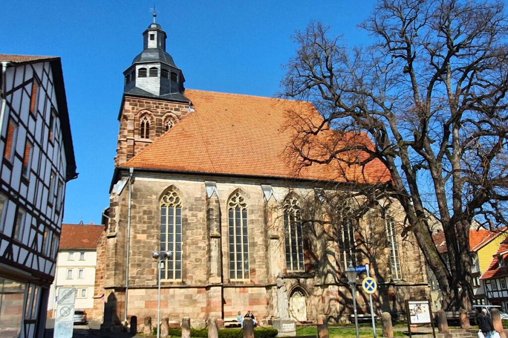 Die gotische Marktkirche St. Dionys in Eschwege mit ihrem markanten Turm und großen Kirchenfenstern unter blauem Himmel.
