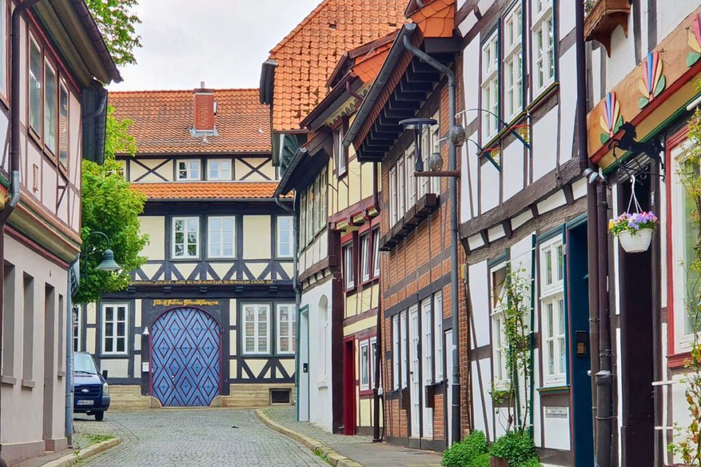 Eine malerische Gasse in Northeim mit Fachwerkhäusern und einer markanten blauen Tür mit Rautenmuster.