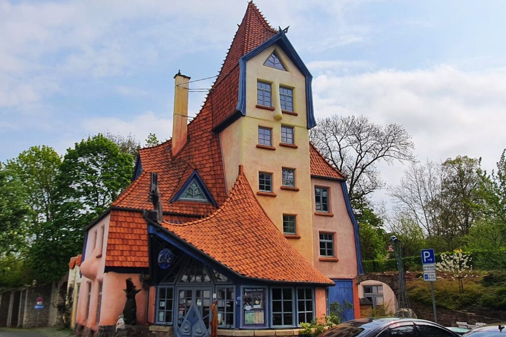 Die fantastische, organisch geformte Architektur des „Theaters der Nacht“ in Northeim mit einem spitzen blauen Giebel.