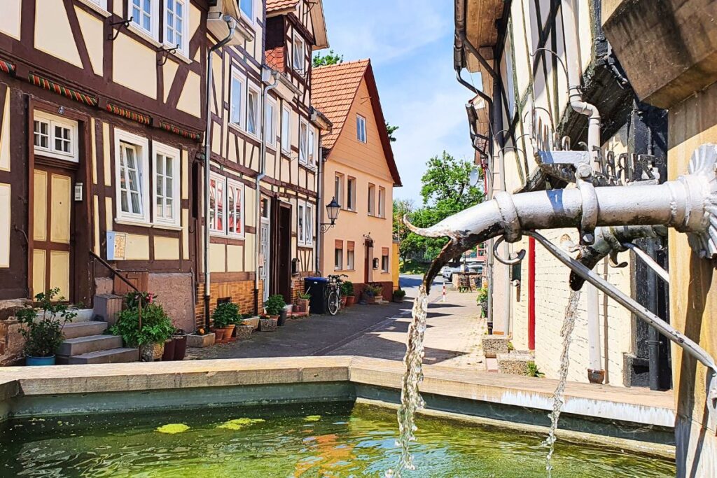 Ein historischer Brunnen in einer engen Gasse des Viertels „Die Türkei“ in Rotenburg an der Fulda, umgeben von wunderschön restaurierten Fachwerkhäusern.
