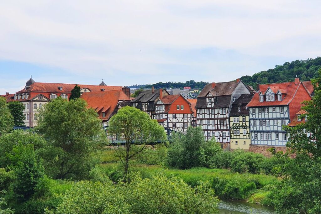 Panorama-Blick auf die geschlossene Reihe bunter Fachwerkhäuser am Ufer der Fulda in Rotenburg unter leicht bewölktem Himmel.