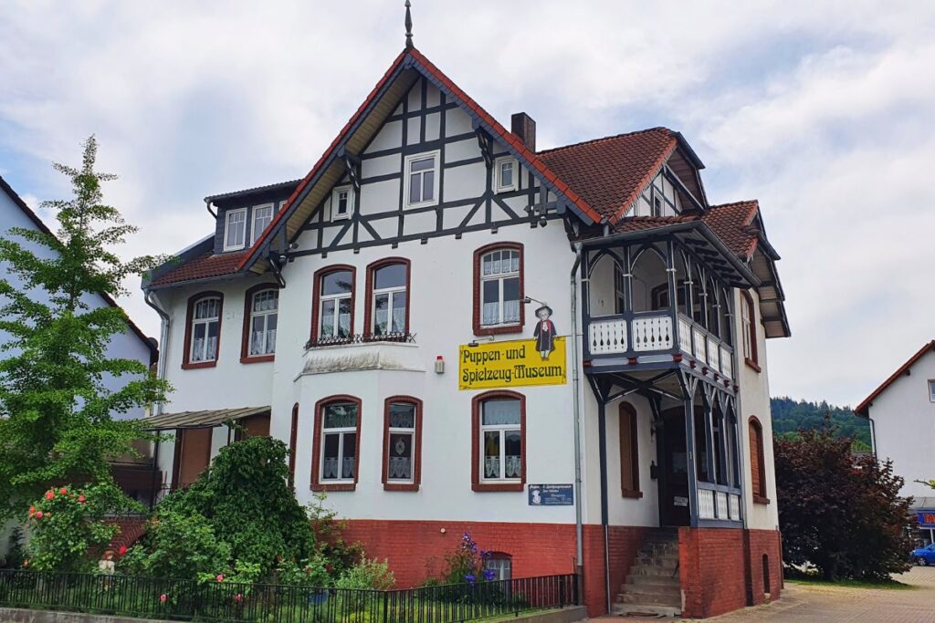 Das Puppen- und Spielzeugmuseum in Rotenburg an der Fulda, ein weißes Wohnhaus mit Veranda und einem gelben Hinweisschild an der Fassade.