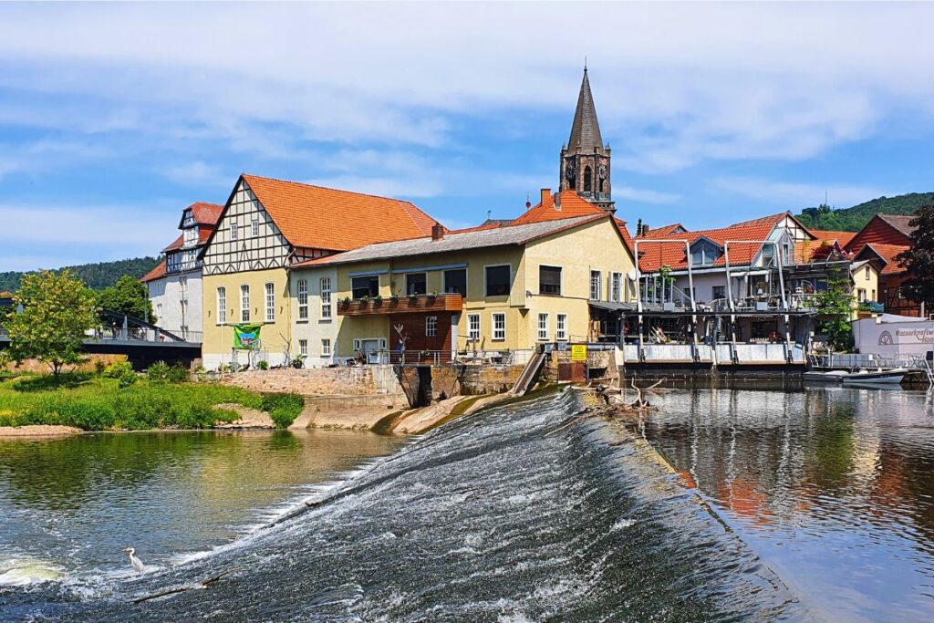 Das fließende Wasser des Fuldawehrs in Rotenburg, im Hintergrund historische Gebäude und der Turm der Jakobikirche.