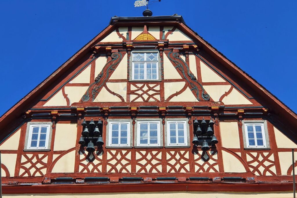 Detailaufnahme des Glockenspiels mit kleinen dunklen Glocken an einem prachtvollen Fachwerkgiebel des Rathauses in Rotenburg.