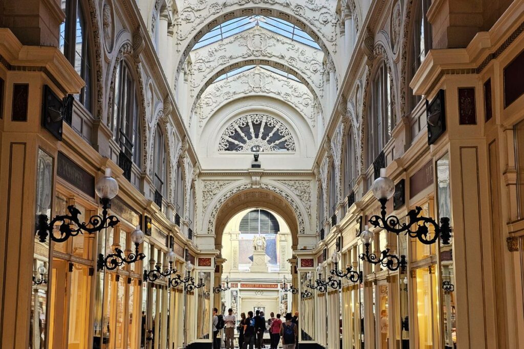 Die prachtvolle dreistöckige Passage Pommeraye in Nantes mit einem hohen Glasdach, verzierten Treppenaufgängen und weißen Skulpturen.
