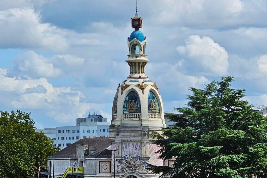 Der dekorative, gelb-blaue Turm der ehemaligen Keksfabrik LU (Tour LU) in Nantes mit goldener Verzierung vor einem bewölkten Himmel.