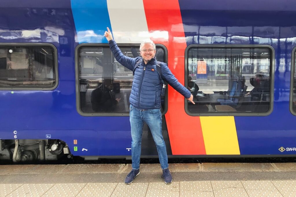 Nicolo Martin steht bereit für die Abfahrt auf einem Bahnsteig vor einem modernen Regionalzug.