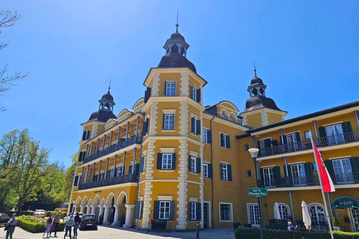 Das berühmte, sonnengelbe Schloss Velden am Wörthersee unter strahlend blauem Himmel im hellen Sonnenlicht.