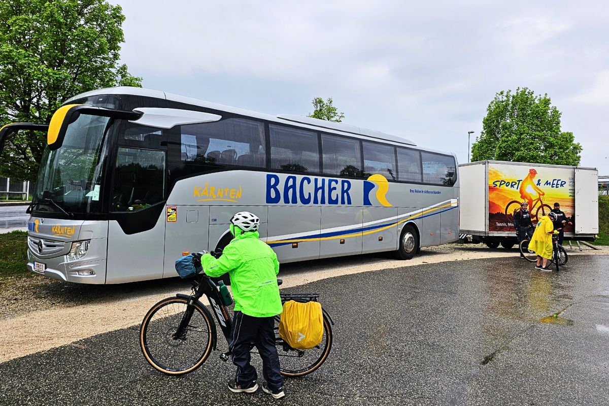 Ein moderner Reisebus mit einem großen Fahrradanhänger steht bereit für den Support und Rücktransfer der Velovista-Radfahrer in Kärnten.