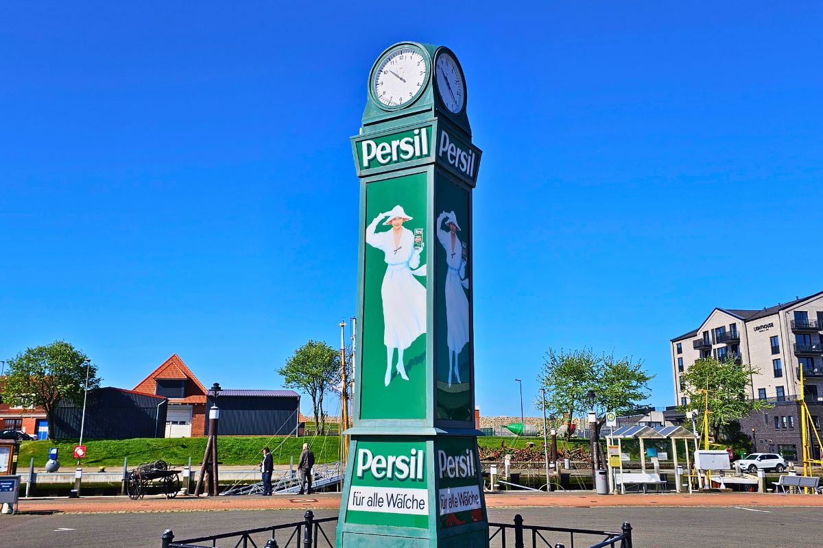 Die grüne, nostalgische Persiluhr inmitten des belebten Ankerplatzes in Büsum an einem sonnigen Tag.