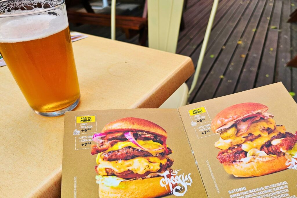 Ein frisch gezapftes, helles Craft Beer steht auf einem Tisch neben einer aufgeklappten Speisekarte mit saftigen Burgern im Restaurant Skapto Iskar in Sofia.