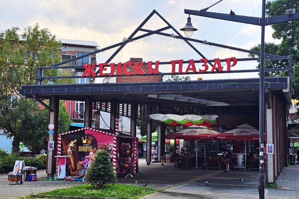 Der große überdachte Eingang zum traditionellen Frauenmarkt Zhenski Pazar in Sofia mit einem auffälligen roten kyrillischen Schriftzug.
