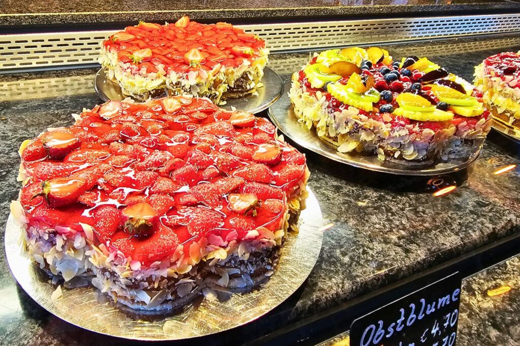 Prächtige, farbenfrohe Obsttorten und Erdbeerkuchen verziert mit Mandelsplittern in der Verkaufstheke des traditionsreichen Café Schubart in Coburg.