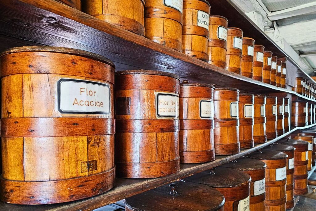Historische, beschriftete Holzfässer auf alten Regalen im geschichtsträchtigen Kräuterlager der Hof-Apotheke in Coburg.