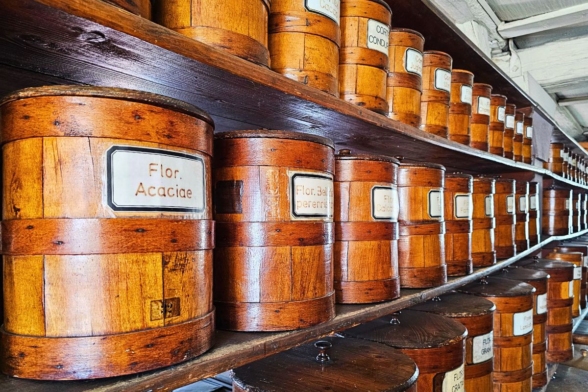 Historische, beschriftete Holzfässer auf alten Regalen im geschichtsträchtigen Kräuterlager der Hof-Apotheke in Coburg.