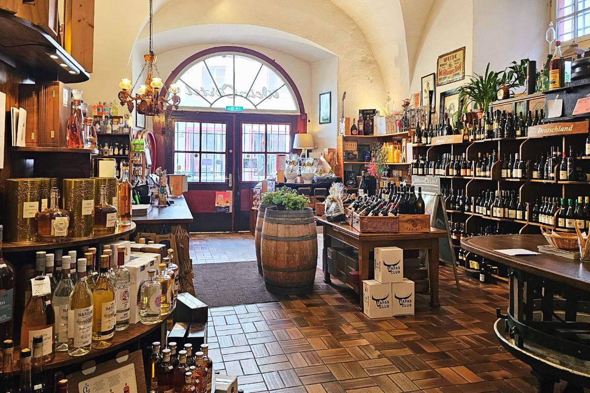 Der gemütliche, historische Verkaufsraum von Wein Oertel in Coburg mit hohen Gewölbedecken, rustikalen Weinfässern und Regalen voller erlesener Weinflaschen.