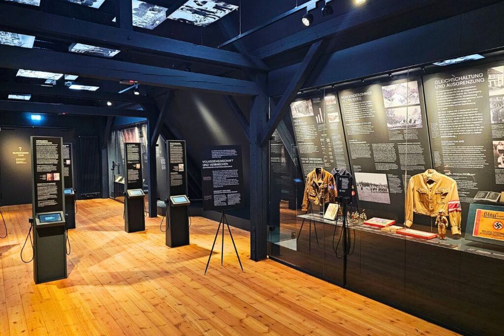 Ein moderner, dunkel gestalteter Ausstellungsraum im Dithmarscher Landesmuseum in Meldorf mit historischen Exponaten und Schautafeln zur Regionalgeschichte.