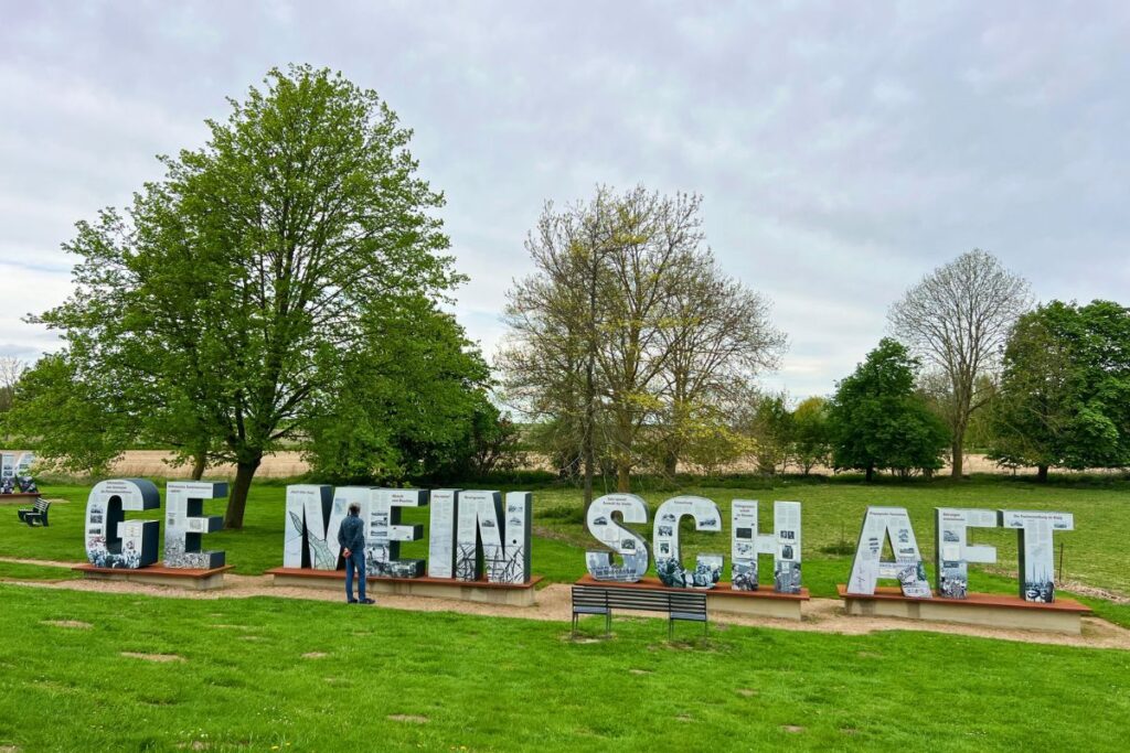 Der Lernort Neulandhalle im Dieksanderkoog mit großen, begehbaren Buchstaben des Wortes GEMEINSCHAFT mit Informations-Schautafeln.