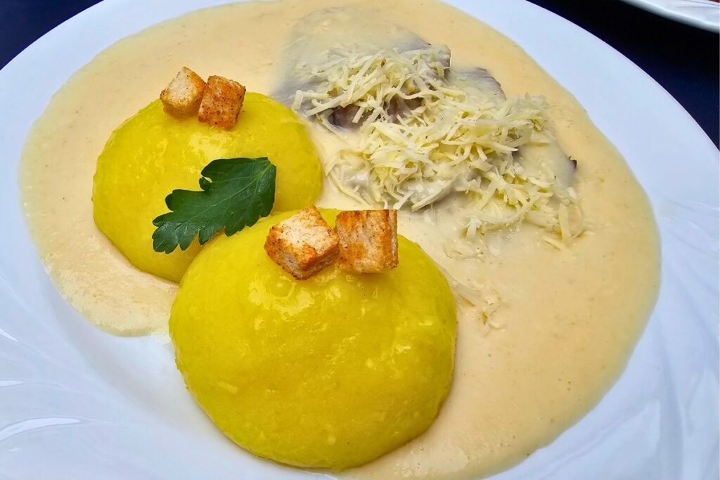 Zwei leuchtend gelbe Coburger Rutscher garniert mit Croutons und Petersilie neben zartem Fleisch in cremiger Meerrettichsoße mit frisch geriebenem Kren im Münchner Hofbräuhaus Coburg.