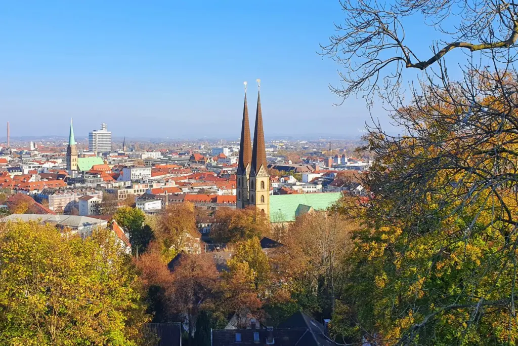 Weitblick über die Dächer der Bielefelder Altstadt mit den markanten Doppeltürmen der Neustädter Marienkirche im sonnigen Herbstlicht.
